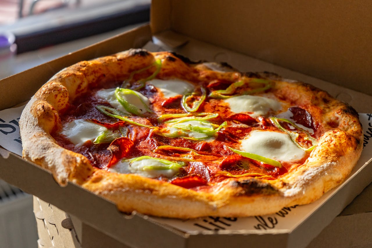 about-us-01 Tasty Neapolitan pizza with fresh ingredients in a cardboard box, perfect for takeout.