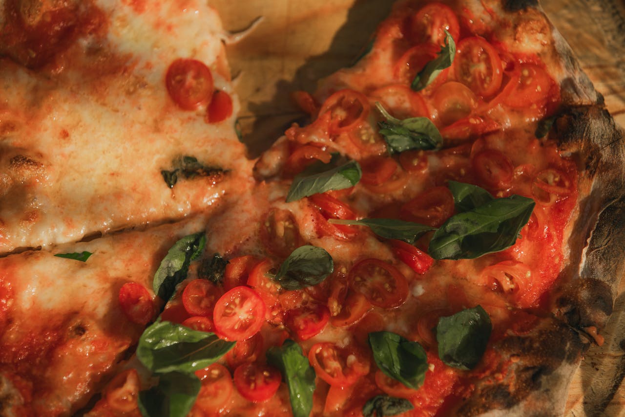 about-us-02 Top view of a baked Margherita pizza with cherry tomatoes, mozzarella, and basil leaves.